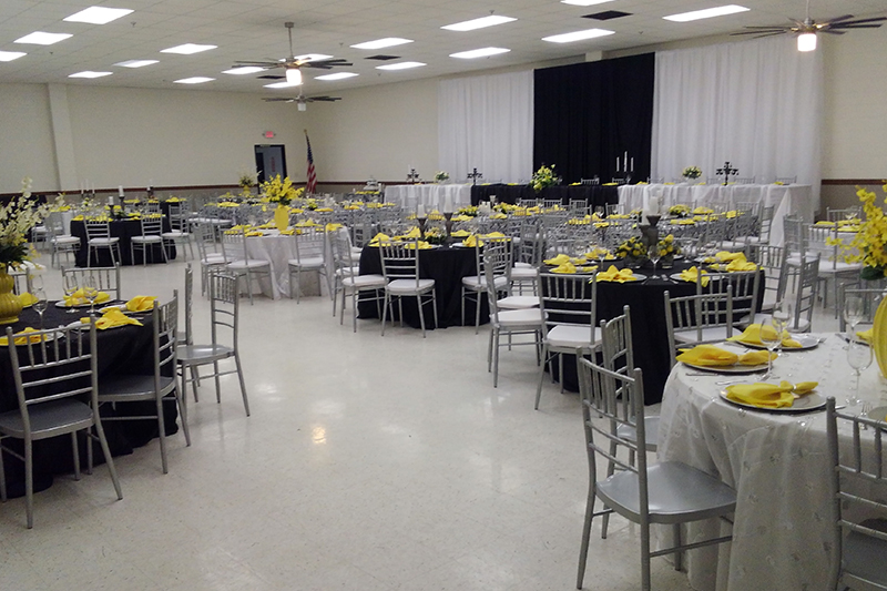 Reception hall with black linens and bright yellow napkins